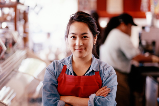 A lady wearing an apron in a cafe